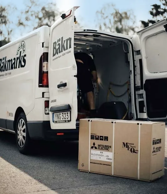 Bäkmarks skåpbil med bakdörrarna öppna och en Mitsubishi-kartong framför